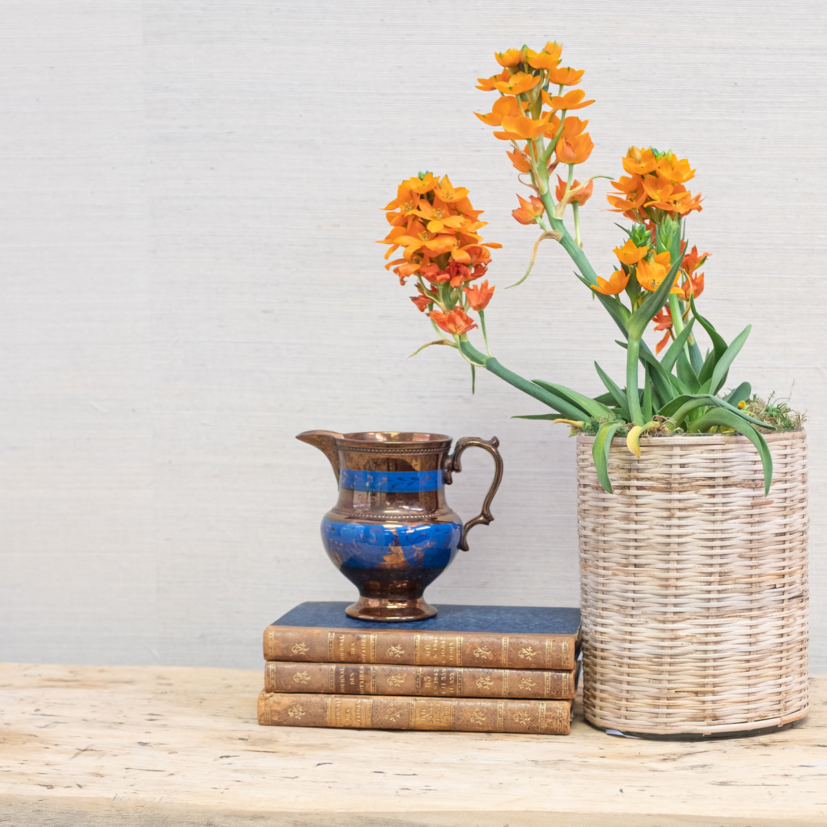 blue and gold lusterware with orange plant and stack of antique books