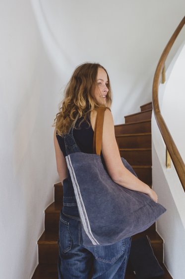 linen tote bag on the shoulder of woman walking up stairs