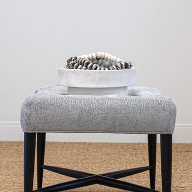 close up of upholstered stool with bowl of beads